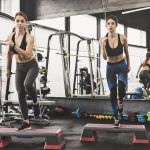 Two fit attractive women doing workout with steppers in the gym